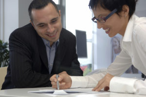 coach mentoring shown by two people at a desk smiling