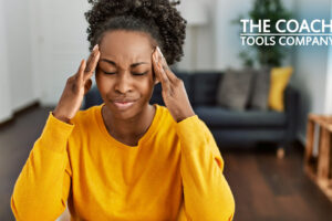 Woman in pain holding head in hands wearing yellow sweater