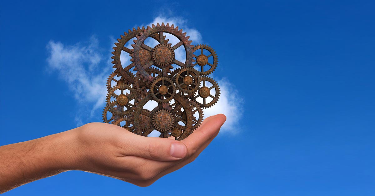 Hand Holding Metal Cogs Against Blue Sky