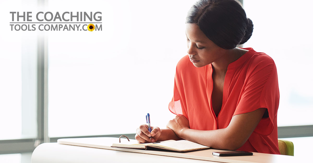 Leader journaling at desk wearing orange shirt