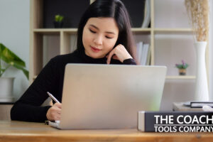 Coach at Desk Journaling with Laptop