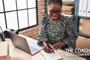 Happy client at desk with laptop working on goals on notepad