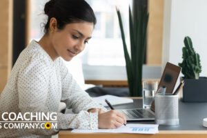 Coach or Client at desk completing a coaching tool with pen and laptop