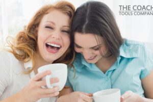 Two happy young female friends with coffee cups enjoying a conversation