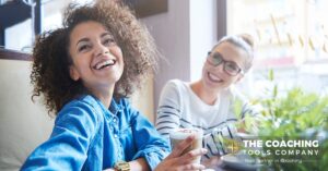 Two women smiling and sharing a coffee, symbolising gratitude, connection, and supportive relationships in coaching.