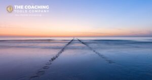 A coastal path revealed in shallow water at sunrise, symbolising clarity and a coaching journey unfolding over time.