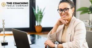 Professional woman working thoughtfully at a laptop, reflecting on her coaching niche