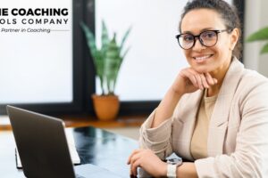 Professional woman working thoughtfully at a laptop, reflecting on her coaching niche